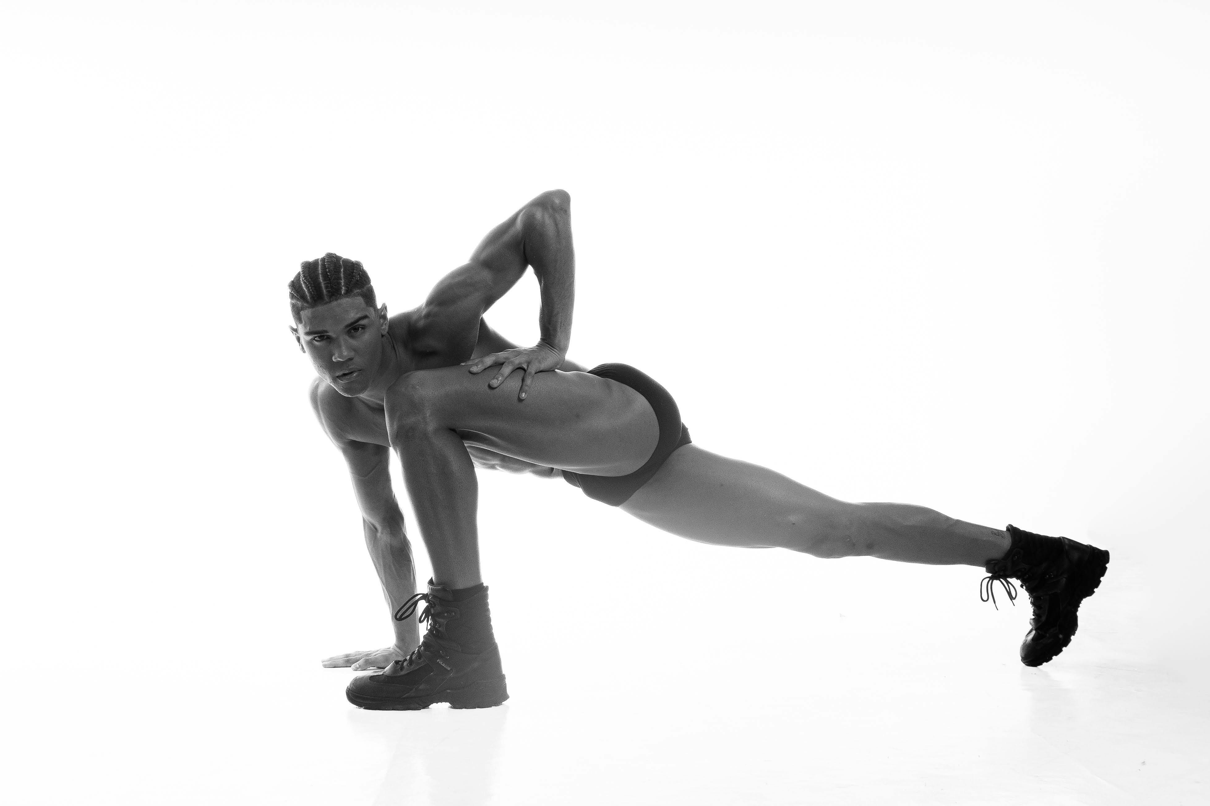 Artistic black and white portrait capturing a male model in a striking pose, emphasizing strength and elegance.